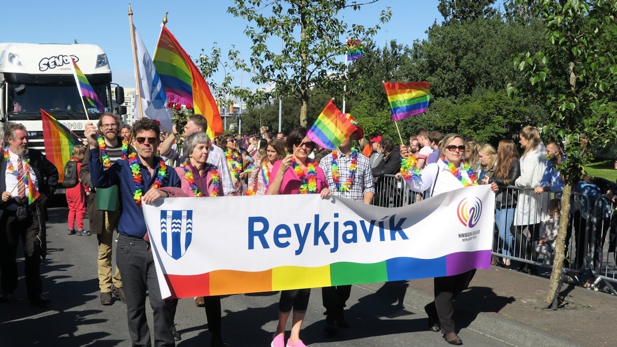 a group of people walking down a street holding a rainbow flag